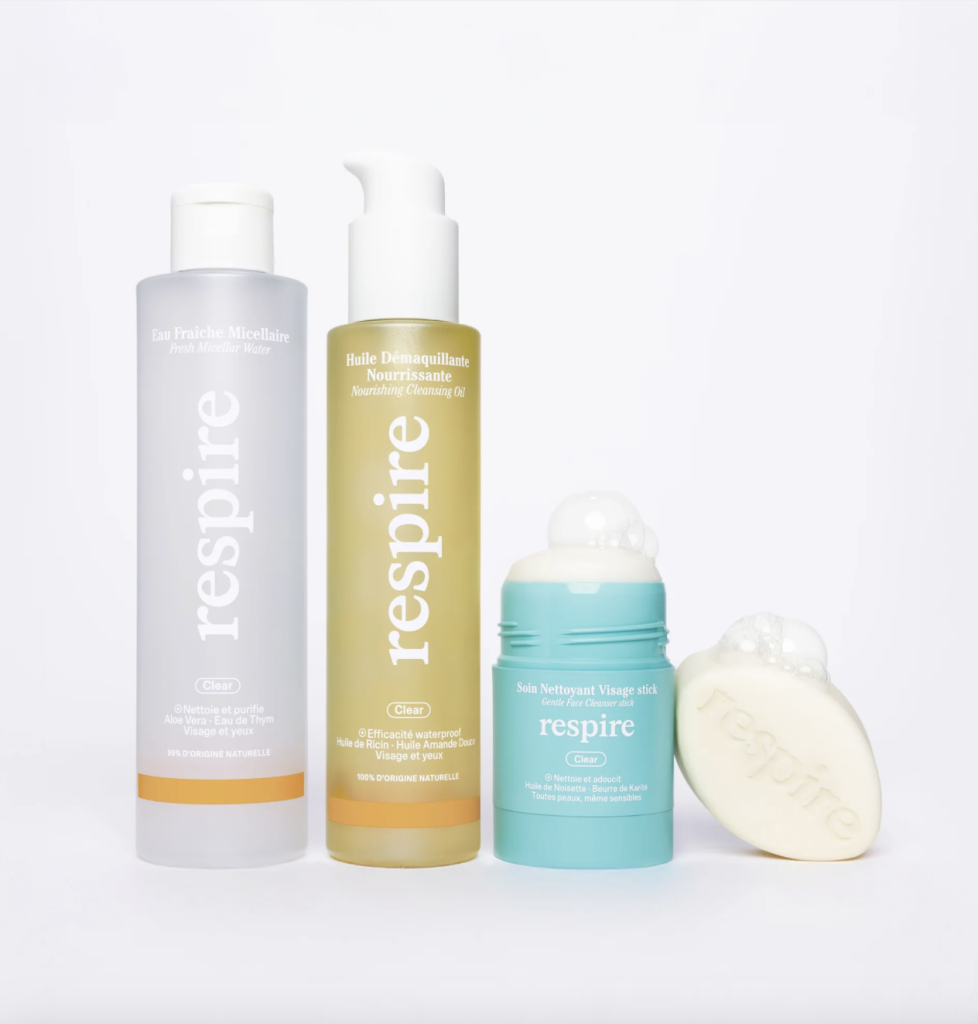 La photo présente une gamme de produits de soin de la marque Respire sur un fond blanc épuré. On y voit :

Une eau micellaire fraîche en flacon transparent avec un bouchon blanc, formulée avec de l’aloe vera et de l’eau de thym.
Une huile démaquillante nourrissante en flacon pompe jaune translucide, contenant de l’huile de ricin et d’amande douce.
Un soin nettoyant visage en stick dans un emballage bleu clair, avec de la mousse sur le dessus, indiquant son utilisation.
Un savon solide blanc, marqué du logo Respire, avec de la mousse pour illustrer son efficacité nettoyante.
L’ensemble met en avant des produits naturels et doux pour la peau, avec un design minimaliste et coloré.