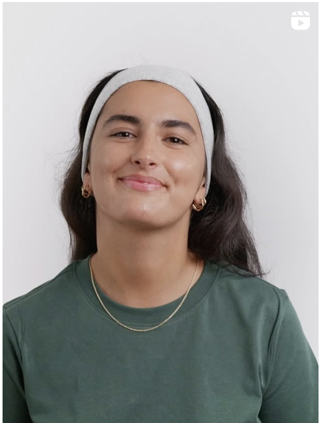 L’image montre une jeune femme souriante, portant un bandeau gris et un t-shirt vert foncé. Elle a les cheveux longs et foncés, et porte des boucles d’oreilles dorées ainsi qu’un collier fin. Son expression est détendue et naturelle.

Le fond est blanc et minimaliste, mettant en valeur son visage et son apparence. Cette image pourrait être issue d’une vidéo ou d’un tutoriel de soins, étant donné la simplicité du cadre et du bandeau qui suggère une préparation pour une routine beauté.
