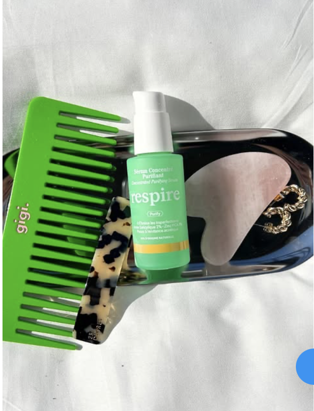 Cette image présente un flacon du Sérum Concentré Purifiant de la marque Respire, placé sur un plateau noir accompagné d’accessoires de coiffure.

Au centre : Le sérum, dans son flacon vert avec une pompe blanche, est conçu pour éliminer les imperfections grâce à une formulation à base d’acide salicylique et de zinc PCA, idéale pour les peaux à tendance acnéique.
À gauche : Un peigne vert vif marqué "gigi.", qui apporte une touche dynamique et colorée à la composition.
En bas : Une barrette à motif léopard, ajoutant une touche d’élégance et de sophistication.
À droite : Un plateau en verre noir avec des détails dorés et une pince à cheveux effet écaille, renforçant un univers chic et minimaliste.